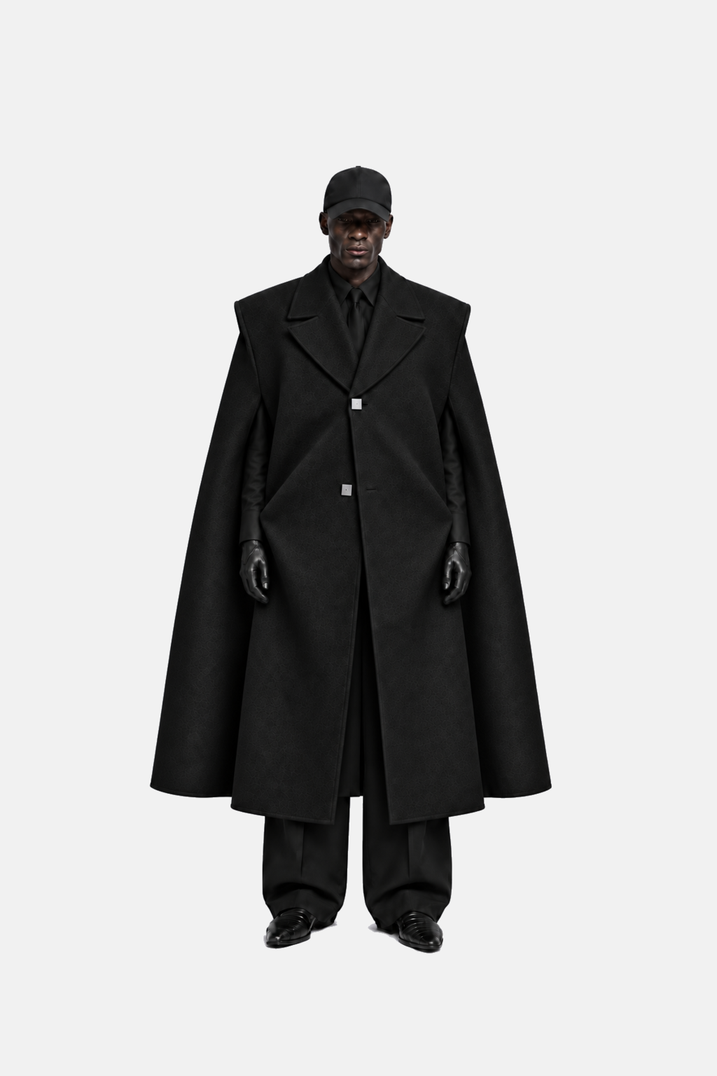 Front fit view of black cape coat on model, with straight arms and black tailored styling