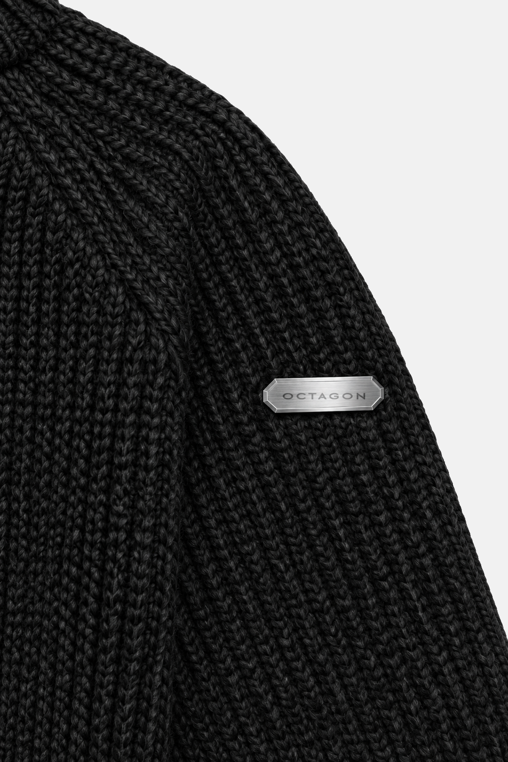 Octagon metal tag on the upper sleeve of black knit