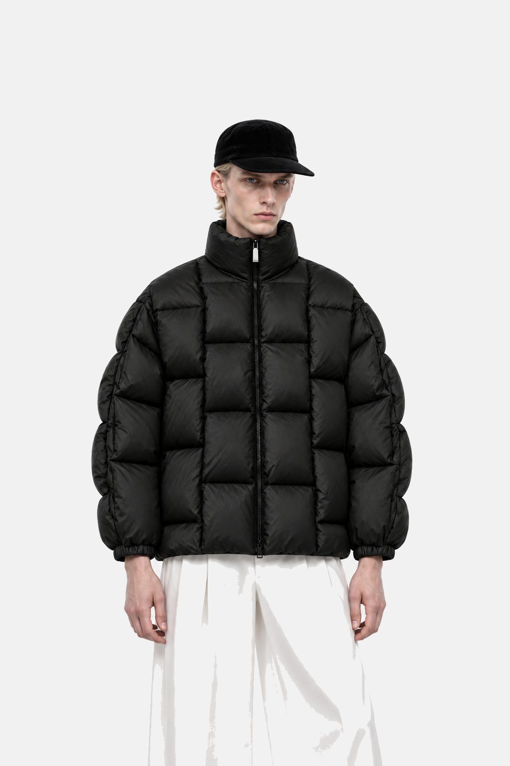 Blond male model wearing the black OCTAGON Diagram Puffer with white silk trousers, front fit view