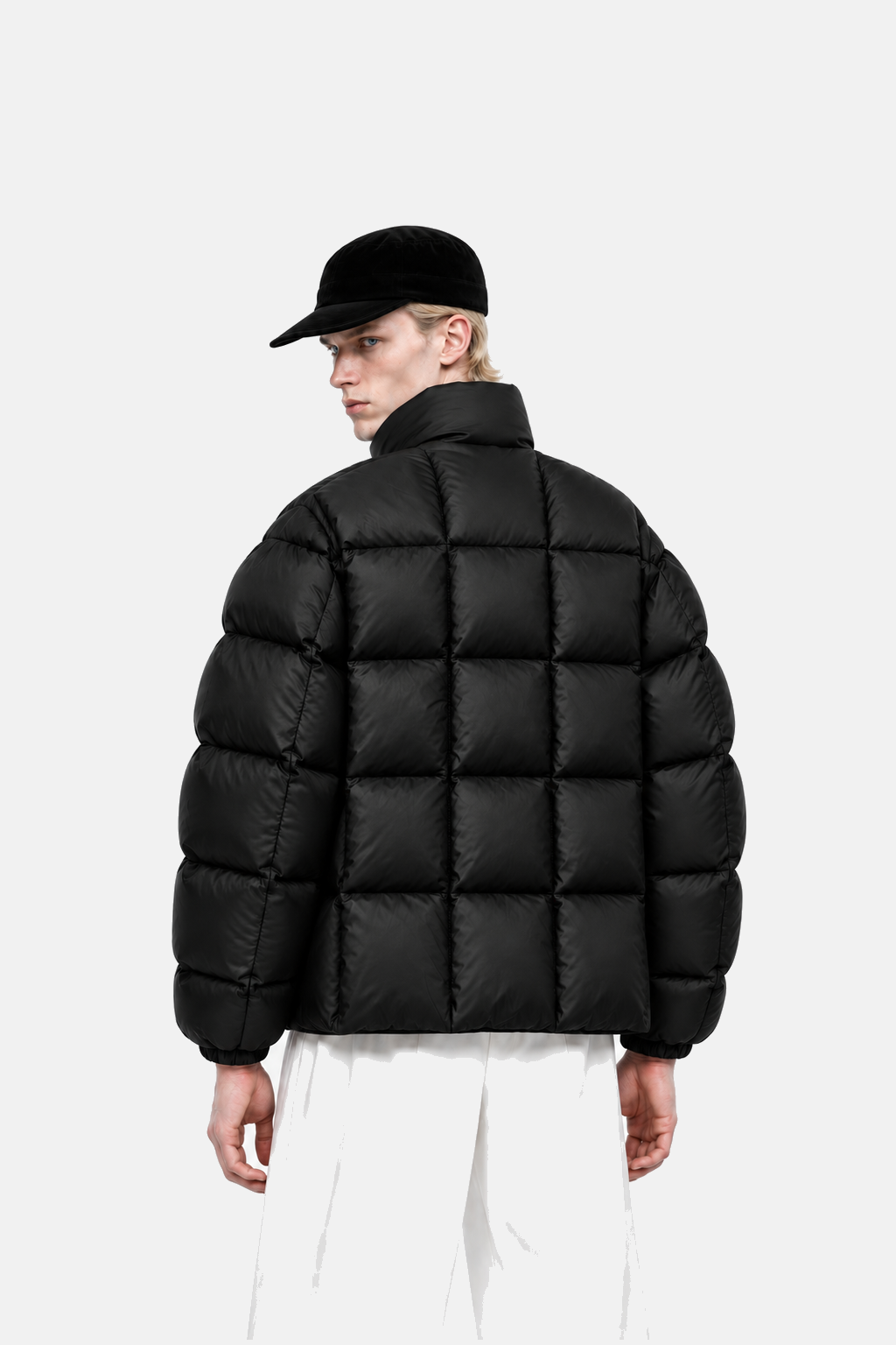 Blond male model wearing the black OCTAGON Diagram Puffer, rear view showing the square quilting grid
