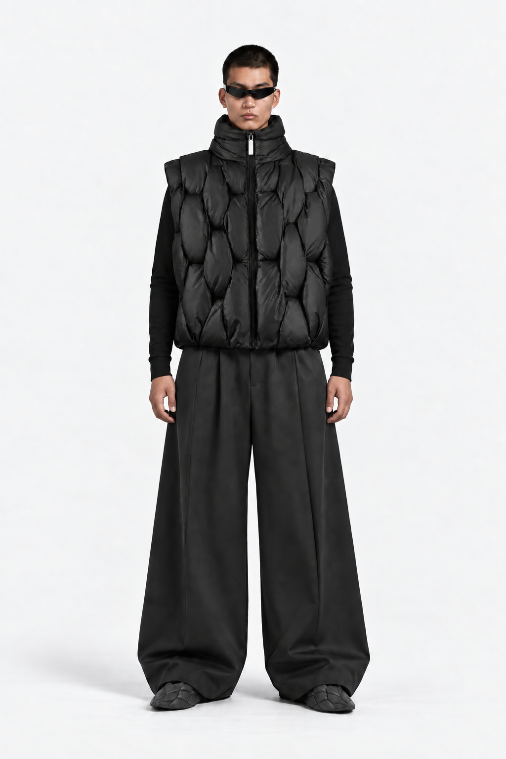 Front view of model wearing the OCTAGON Pentagon black puffer vest and graphite Foam Runners