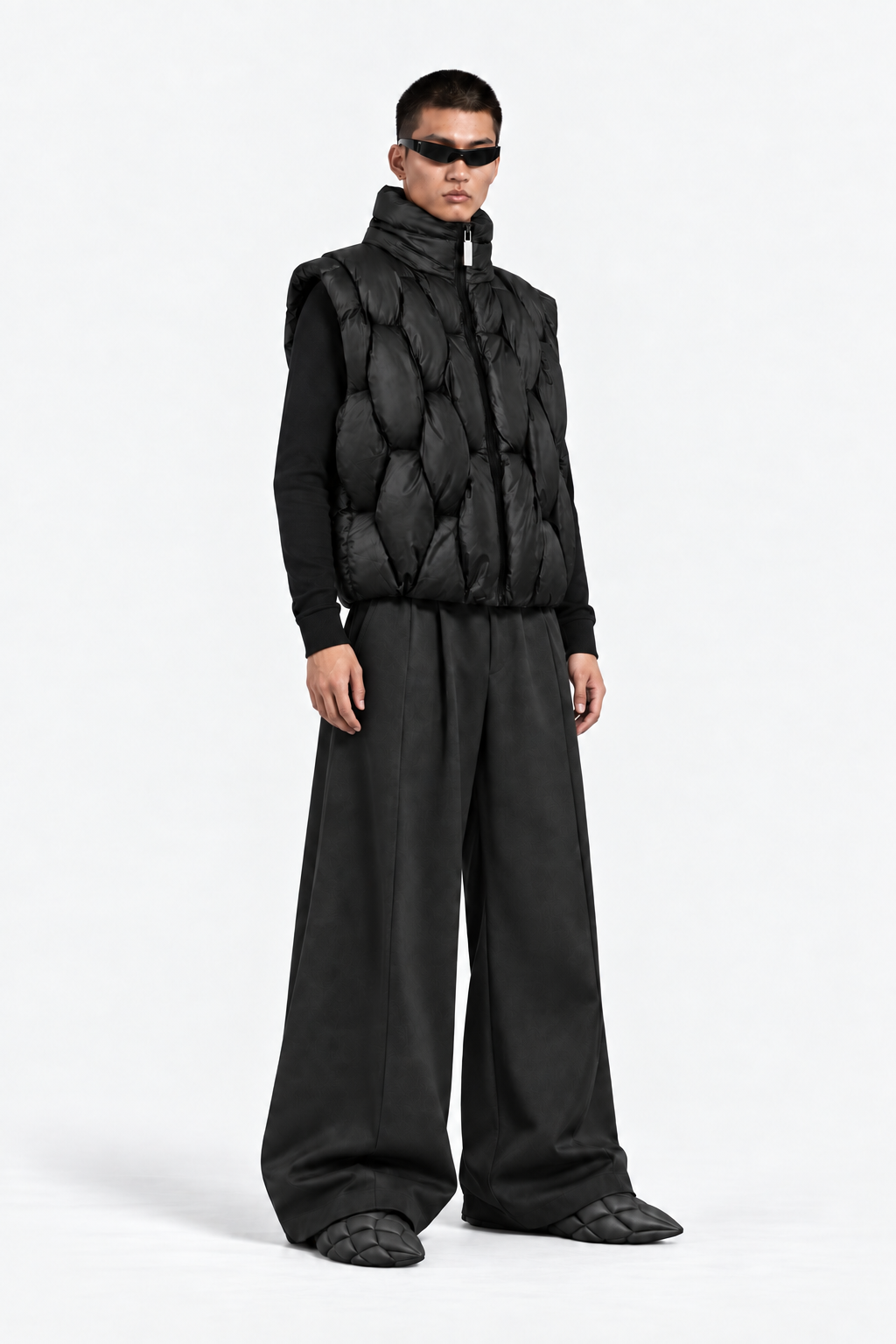 Three-quarter view of model wearing the OCTAGON Pentagon black puffer vest and graphite Foam Runners